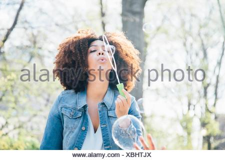 Front view of mid adult woman blowing bubbles, eyes closed, looking up