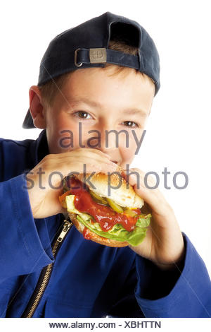 overalls wearing boy young biting hamburger into fallen sitting tree alamy