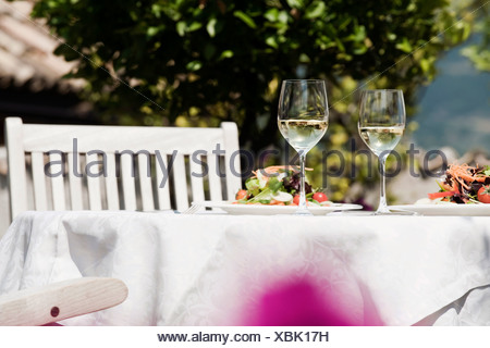 Italy, South Tyrol, Laid table, with mixed salad on plates and two glasses with white wine