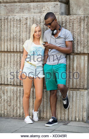 lachende junge freunde im sommer in der stadt mit mobiltelefon