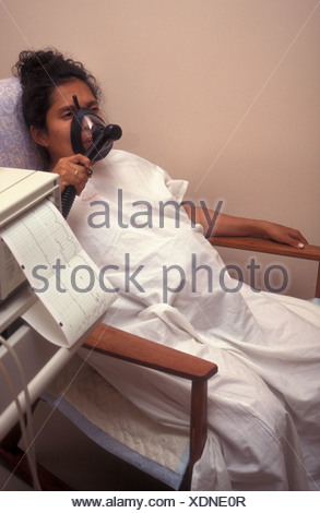 Pregnant Hispanic woman in labour in hospital using gas and air mask ...