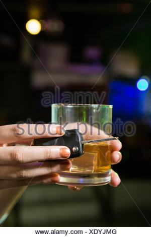 Woman holding a glass of whiskey and car keys