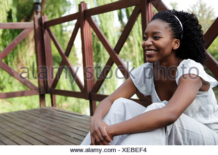 Young African woman sits on a wooden deck