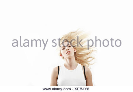 Studio portrait of young woman shaking long blond hair
