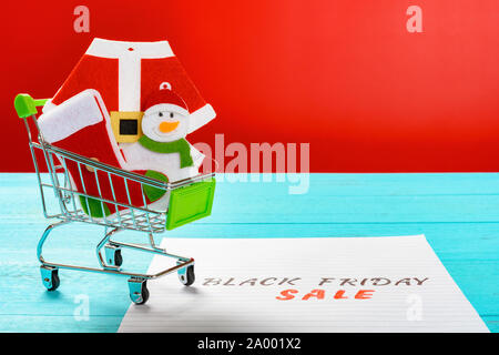 Papier mit schwarzer Freitag Verkauf mit einem Warenkorb mit Weihnachten Dekoration geschrieben Stockfoto