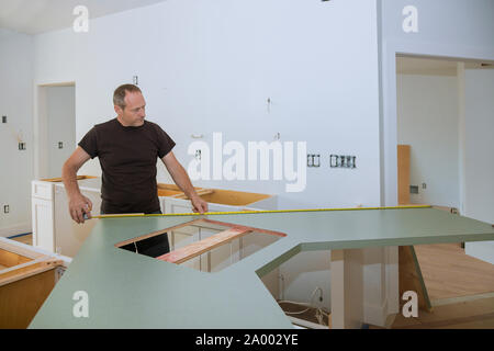Mann mit Maßband zum Messen auf hölzernen Küchentisch in Möbel für Home Improvement. Stockfoto