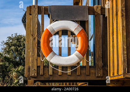 Leben Boje hängen auf einer Holzterrasse. Leben ring Boje auf einem Holzdeck, lebensrettenden Konzept in optimistisch helle Farben Stockfoto