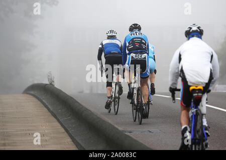 Radfahrer, Reiten, Fahrradverleih, Pendler, in dichtem Nebel, ein kalter Tag schlechtes Wetter. Stockfoto