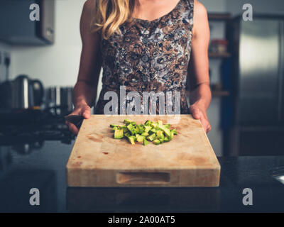 Eine junge Frau wird hacken Avocado in Ihre moderne Küche Stockfoto