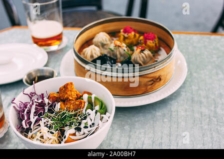 Panasiatisches essen - Salat Schüssel und verschiedenen Dim Sums. Mittagessen für zwei mit Bier Stockfoto