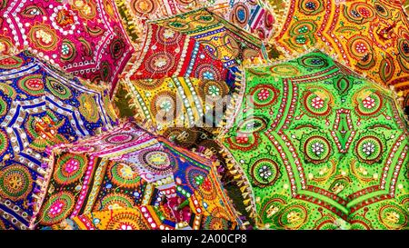 Eine bunte Reihe von Sonnenschirmen mit lebhaften Farben und komplizierten Mustern, für den Verkauf als Souvenirs auf einer Straße in Jaipur, Indien. Stockfoto