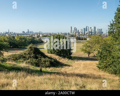 Blick vom Greenwich Park auf die Universität mit den Wolkenkratzern von Canary Wharf hinter der Themse, Greenwich, London Stockfoto