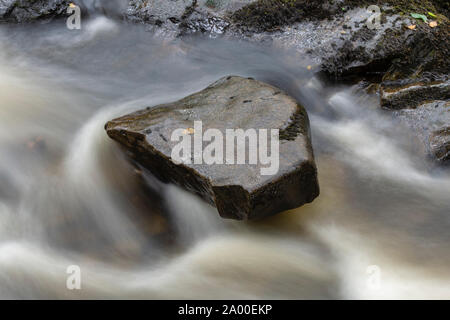 Rock auf der Cordorcan brennen durch schnell fließendes Wasser in den Wald von Cree Nature Reserve, Newton Stewart, Dumfries und Galloway, Schottland umgeben Stockfoto