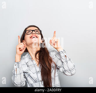 Schön aufgeregt Business woman in Gläser suchen und nach zwei Finger auf Copy space Hintergrund. Closeup Portrait Stockfoto