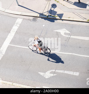 Wien, Österreich - 13 September, 2019: Frau auf einem Fahrrad, zwischen dem linken und dem rechten Pfeil Zeichen - Ansicht von oben mit langen Schatten. Stockfoto