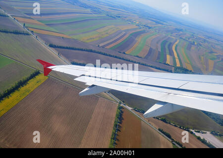 Weiß Flugzeugflügel gekippt im Tiefflug über die Getreidefelder Muster. Stockfoto