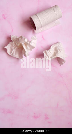 Weiß zerknittert Seidenpapier und Klopapierrolle auf einem rosa Marmor Hintergrund. Stockfoto
