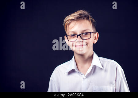 Das Porträt einer niedlichen smilling Junge auf dem schwarzen Hintergrund Stockfoto