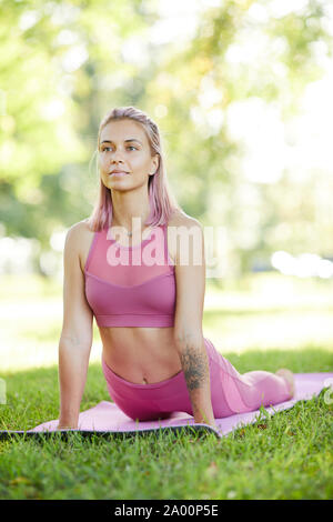 Junge gesunde Frau liegend auf trainingsmatte und Stretching während Ihrer sport training im Park Stockfoto