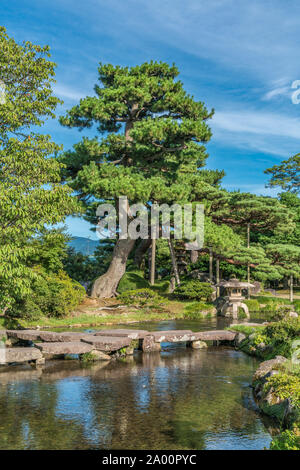 Kanazawa, Ishikawa, Japan - 22. August 2018: Japanische Pinien und einem Stein Laterne (Ishidoro) in einem Teich im Garten Kenrokuen Stockfoto