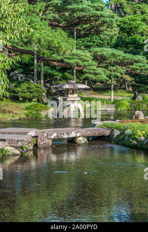 Kanazawa, Ishikawa, Japan - 22. August 2018: Japanische Pinien und einem Stein Laterne (Ishidoro) in einem Teich im Garten Kenrokuen Stockfoto