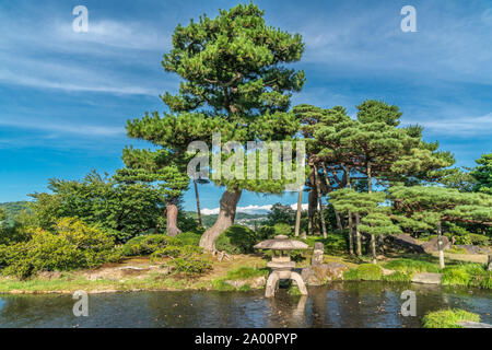 Kanazawa, Ishikawa, Japan - 22. August 2018: Japanische Pinien und einem Stein Laterne (Ishidoro) in einem Teich im Garten Kenrokuen Stockfoto