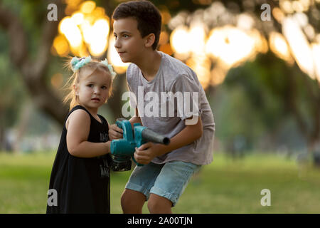 Kinder spielen Reinigung Laub mit einem Gebläse in einem Herbst City Park Stockfoto