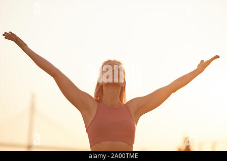 Junge Frau streckte ihre Arme und genießen die Natur bei Sonnenuntergang im Freien Stockfoto