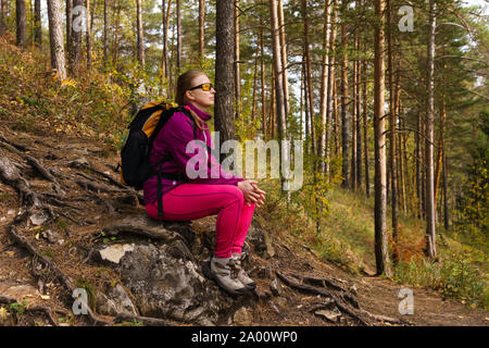 Frau Reisende sitzen auf einem Stein auf den Berg zu den Herbst Wald Stockfoto