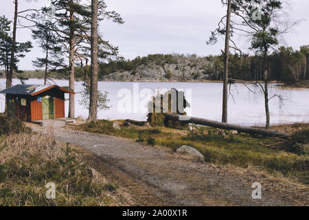 Gefallenen Baum entwurzelt und Outdoor wc Kabine neben gefrorenen See, Bjorno Nature Reserve (Bjorno Naturreservat), Stockholmer Schären, Schweden Stockfoto