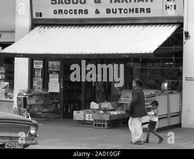 Southall, London 1972. Eine Mutter und Kind zu Fuß entlang der Straße vor einem Lebensmittelgeschäft. Nach Idi Amin bestellt 30.000 Asiaten aus Uganda mit 90 Tagen, die mit britischen Pässen zu England geleitet. Sie wurden gezwungen, ihr Geld, Eigentum und Besitz hinter sich zu lassen. Diese Bilder dokumentieren das Leben für einige der Menschen, wie sie in Southall, westlich von London nieder. Einen Einblick in das Leben vor 47 Jahren für Einwanderer in Großbritannien. Foto von Tony Henshaw Stockfoto