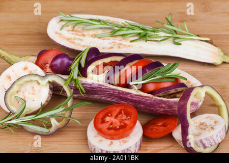 Auberginen gefüllt mit Paprika und Tomaten auf einer hölzernen Tisch. Rosmarin auf das Gemüse. Im rustikalen Stil. Stockfoto