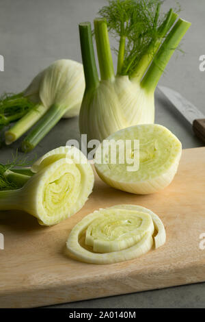 Frische rohe organische Fenchelknolle und Scheiben auf einem Schneidebrett Stockfoto