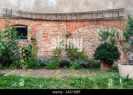 Gemüse- und Kräutergarten gegen eine rustikale Backsteinscheune Wand in der Uckermark, Brandenburg, Deutschland Stockfoto