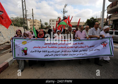 Palästinenser März halten ein Banner und Flaggen vor dem Sitz des Roten Kreuzes während des Protestes die Freilassung der palästinensischen Gefangenen in israelischen Gefängnissen im südlichen Gazastreifen. Stockfoto