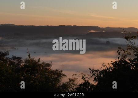 Die eisigen Morgendämmerung in den Bergen von Jaguari, Ortschaft Chapadão, RS, Brasilien. Morgen intensiver Nebel und die Sonne am Horizont. Weinregion und Stockfoto