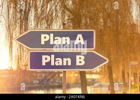 Zwei blaue Pfeile in die entgegengesetzte Richtung mit der Aufschrift Plan A und Plan B mit sonnigen Hintergrund einer Stadt Stockfoto