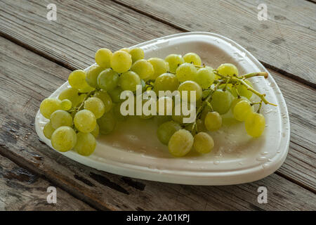 Bündel aus weißen Trauben mit Wassertropfen auf der Platte Stockfoto