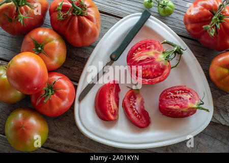 Gruppe von Tomaten mit in Scheiben geschnittenen Tomaten auf Platte Stockfoto