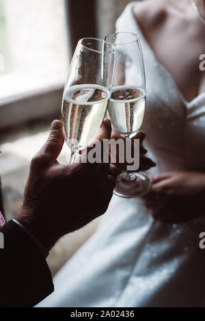 Nahaufnahme von Ehepaar toasten Sektgläser bei der Hochzeit Party. Hände Braut und Bräutigam Anstoßen an der Hochzeit. Stockfoto