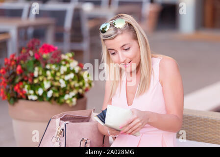 Cute woman in Ihrem Portemonnaie in einem Restaurant mit Terrasse suchen Stockfoto