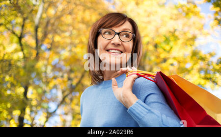 Ältere Frau mit Einkaufstüten über Herbst Park Stockfoto