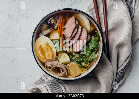 Miso Ramen mit gebratenem Rindfleisch, Shiitake-Pilze, gebratenem Tofu, Lauch und Eier auf konkreten Hintergrund. Ansicht von oben. Im asiatischen Stil Mittagessen Stockfoto