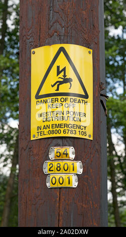 Warnzeichen und Identifikationsnummer auf der hölzernen Stange Unterstützung Overhead Hohe Spannung Fernleitungen, Treherbert, Wales Stockfoto
