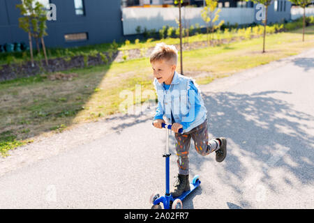 Happy little boy reiten Roller in der Stadt Stockfoto