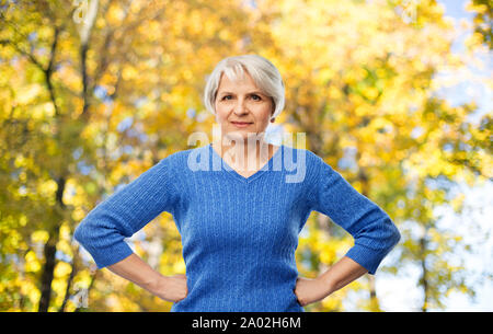 Ältere Frau mit Händen auf den Hüften im Herbst Park Stockfoto