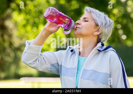 Ältere Frau Getränke Wasser nach dem Training im Park Stockfoto