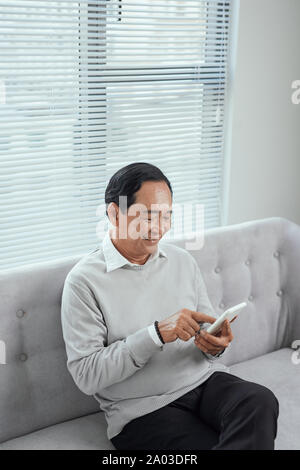 Asiatische senior glücklich mit dem Handy zu Hause Stockfoto