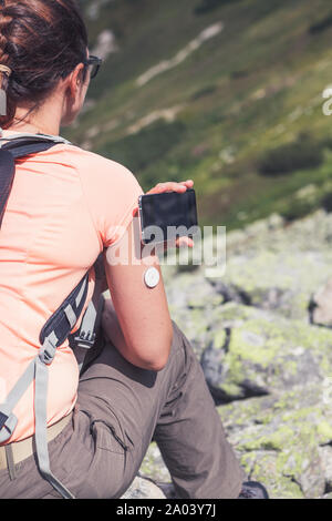 Das aktive Leben der Diabetiker, Frau wandern und Kontrolle der Blutzuckerspiegel über einen Remote Sensor und Handy, neue Technologie sensor Checkup Blutzuckerspiegel Stockfoto