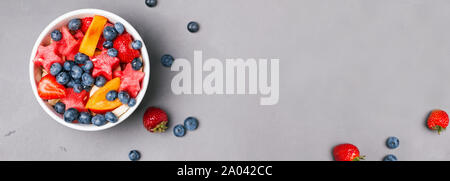 Banner oder Panorama mit Früchten und Beeren in der Schüssel auf dem grauen Hintergrund, Ansicht von oben Stockfoto